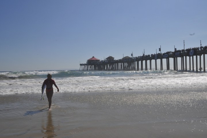 woman walking out of water with surf board