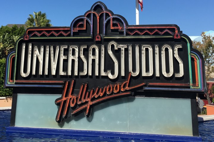 a sign above a store with Universal Studios Hollywood in the background